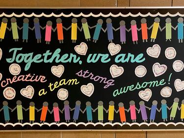 Hallway board with writing, paper hearts and paper pencil crayons.