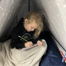 Student working on writing in the tent